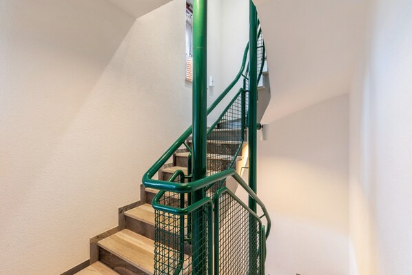 Una escalera con barandillas de metal verde y peldaños de madera.