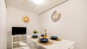 Ein Essbereich mit einem weißen Tisch, blauen Tellern und einer Uhr an der Wand.