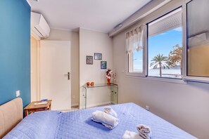A bedroom with a bed, a glass desk, a window with a view, and a door leading to another room. - Rives d'Azur Apt with Sea View Terrace, Menton, France (Menton)