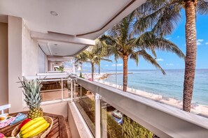 Un balcón con vista al océano, una piña y plátanos sobre una mesa.