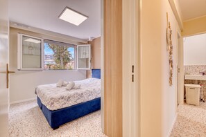 A bedroom with a bed, a window, a door, and a bathroom visible through an open door. - Rives d'Azur Apt with Sea View Terrace, Menton, France (Menton)