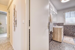 A modern bathroom with a wooden vanity, a towel rack, and a window with a curtain. - Rives d'Azur Apt with Sea View Terrace, Menton, France (Menton)