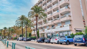 A multi-story hotel with balconies, a parking lot, and palm trees. - Rives d'Azur Apt with Sea View Terrace, Menton, France (Menton)
