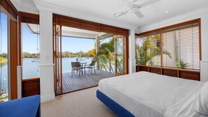 A bedroom with a bed, a ceiling fan, and a view of the water outside. - Riverside Elegance on Noosa Parade (Noosa)