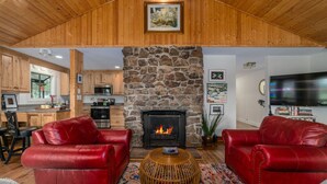 A cozy living room with a stone fireplace, red leather sofas, and a television. - Tranquil home near W&L, VMI (Lexington)