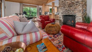 A cozy living room with a stone fireplace, red leather sofas, and a wooden ceiling. - Tranquil home near W&L, VMI (Lexington)