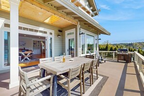 Une terrasse extérieure avec une table et des chaises en bois, un barbecue et une vue sur le paysage.