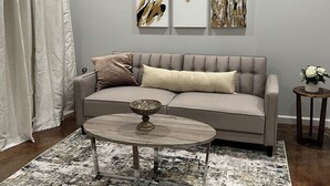 A modern living room with a grey sofa, a round coffee table, and abstract art on the wall.