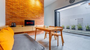 A modern living room with a brick wall, a wooden dining table, and a sofa. - Feels Like Home Villa (Blahbatuh)