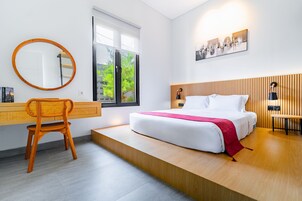 Un dormitorio moderno con cama, sillón, escritorio y ventana.