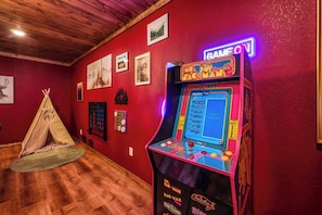 Una habitación con una máquina de arcade Pac-Man, un tipi y varias fotografías enmarcadas en las paredes.
