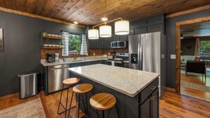 A modern kitchen with a central island, stainless steel appliances, and wooden accents. - *Central! Game Room! Hot Tub!* (Pigeon Forge)