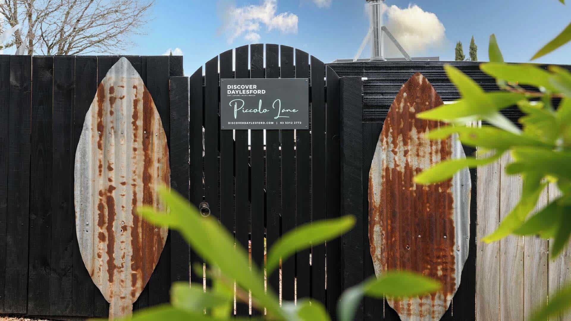 A black metal gate with a sign for 'Discover Dalesford Piccolo Jane'.