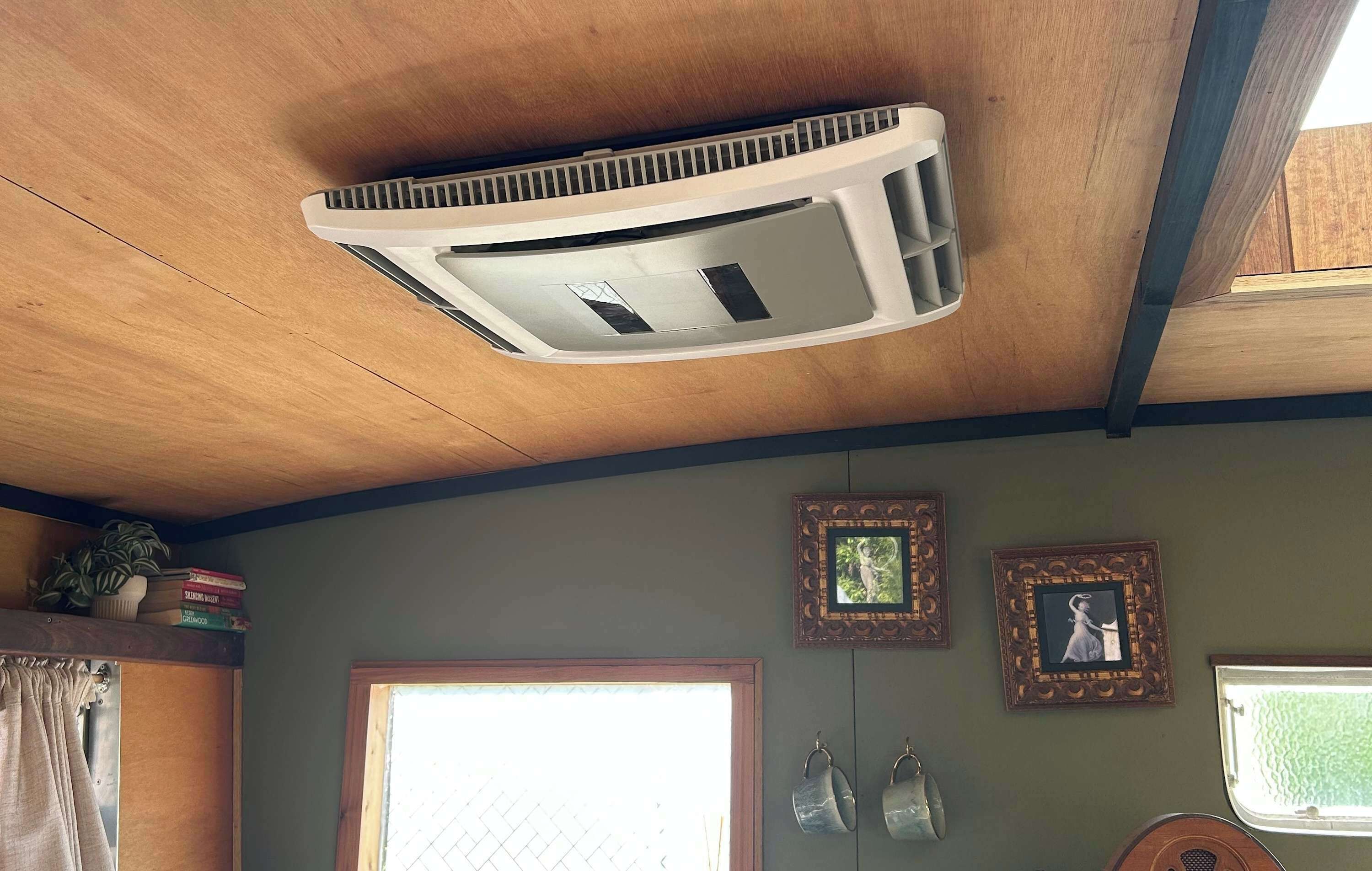 Una habitación con techo de madera, una ventana con cortina y adornos en la pared.