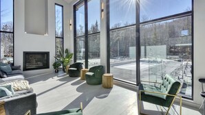 A spacious living area with large windows, a fireplace, and modern furniture.