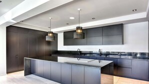 A modern kitchen with a central island, dark cabinetry, and pendant lighting.