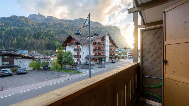 A balcony with a view of a mountain, a street, and buildings with balconies. - New apartment in the center of Canazei (Canazei)