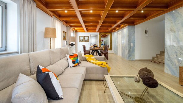 A modern living room with a wooden ceiling, a beige sofa, and a glass coffee table. - Villa Rosa Estoril Retreat by Portugal Portfolio (Estoril)