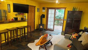 Un salon avec un téléviseur, des tabourets de bar en bois, une cheminée et un canapé.
