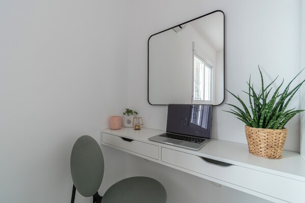 A white desk with a laptop, a mirror, a potted plant, and a green chair. - Satu Granada (Granada)
