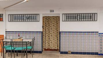 A dining area with a table and chairs, a patterned curtain, and a tiled wall with a number sign above the door.