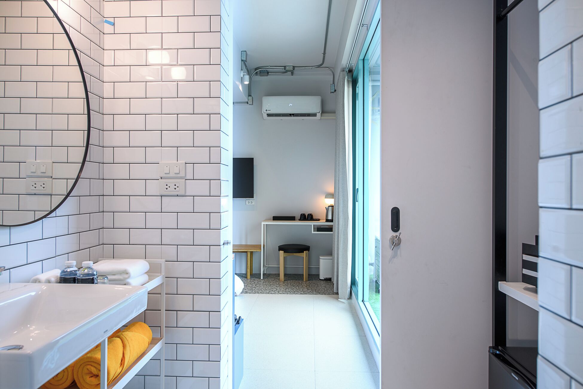 A modern bathroom with white subway tiles, a white sink, and a towel rack.