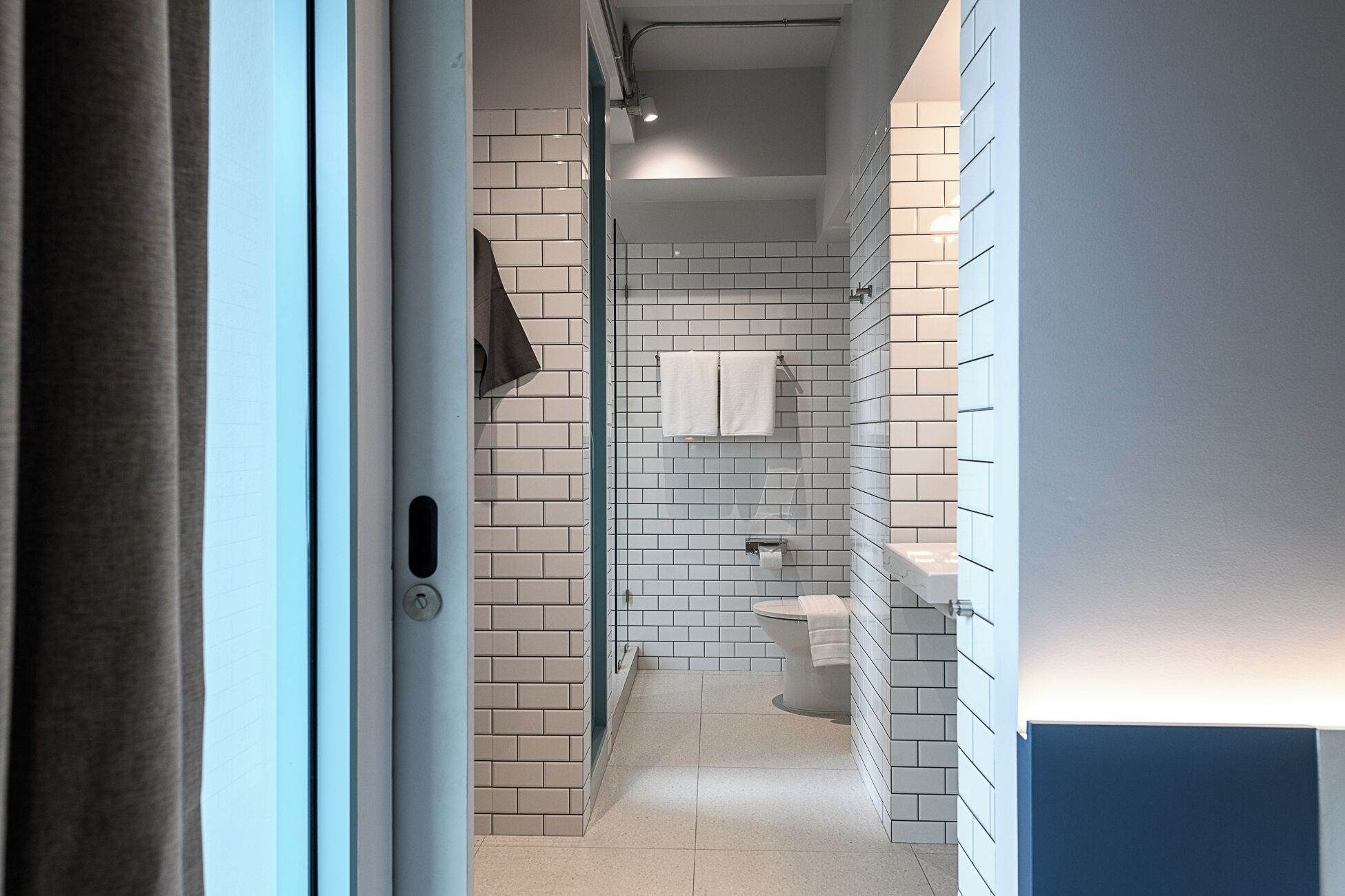 A modern bathroom with white subway tiles, a toilet, and a shower area.