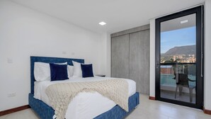 A bedroom with a bed, a view through a sliding door, and a cityscape in the background.
