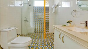 Ein Badezimmer mit Dusche, Toilette, Waschbecken und Fliesenboden mit Muster.