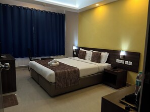 A modern hotel room with a large bed, bedside tables, a desk, and a chair. - Relax Holiday Home,Margao Railway Station  (Margao)