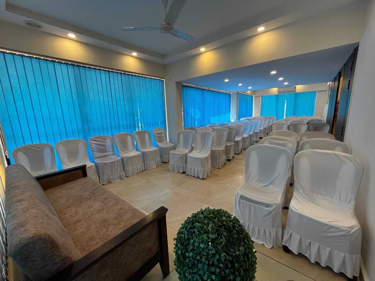 Un salón de conferencias con filas de sillas, un sofá y una planta pequeña.