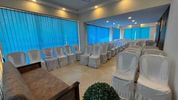 Un salón de conferencias con filas de sillas, un sofá y una planta pequeña.