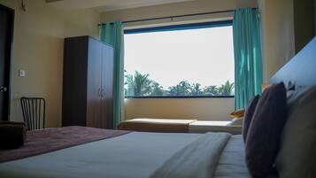 Quarto de hotel com cama, janela com cortinas, guarda-roupa e uma cadeira.