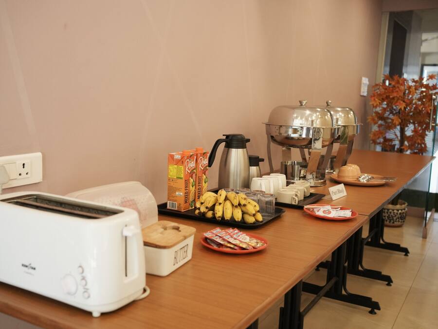 A breakfast setup with a toaster, coffee maker, and various food items on a table.