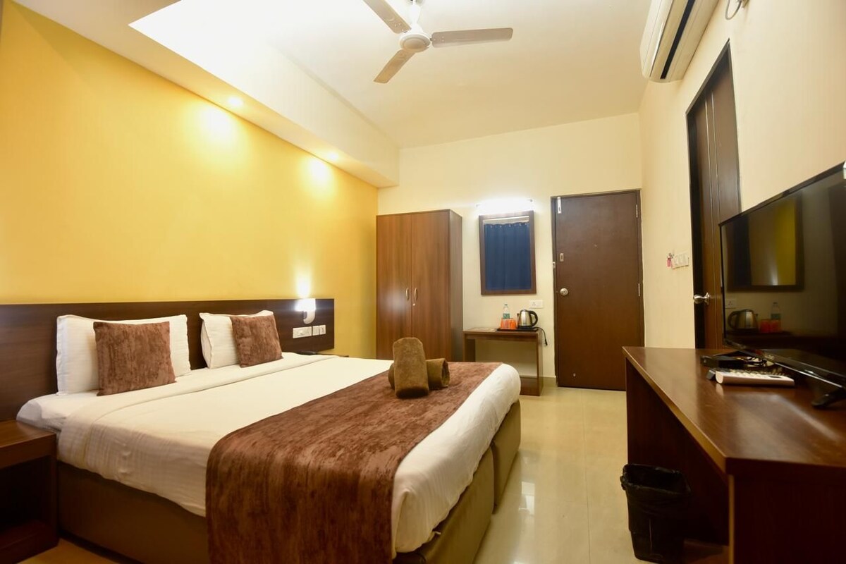 A hotel room with a bed, a desk, a television, and a wardrobe.