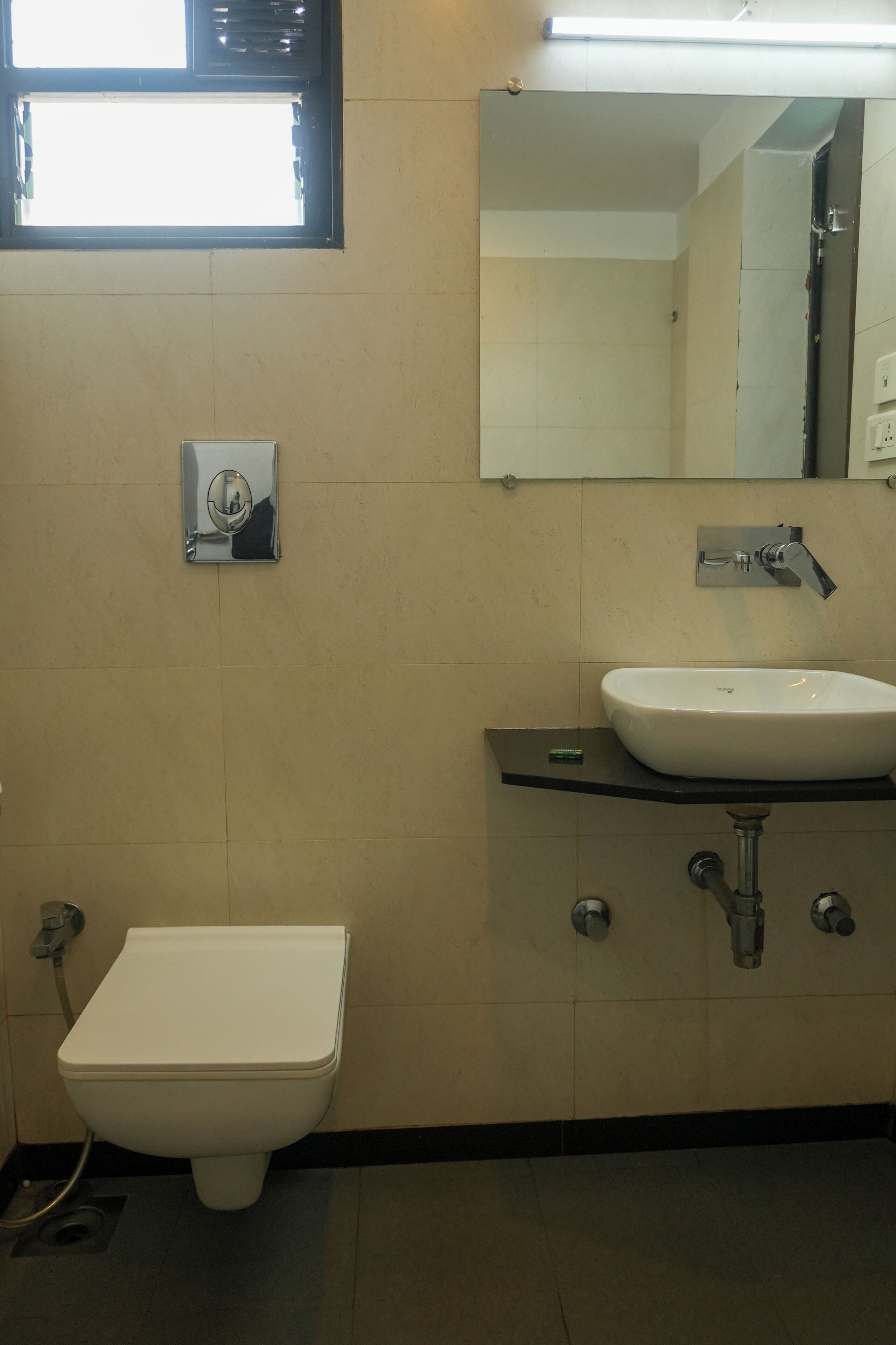 Un bagno con il water, un lavandino, uno specchio e una finestra sopra il lavandino.