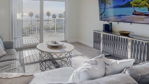 Uma sala de estar moderna com uma televisão grande, uma mesa de centro redonda e um sofá.