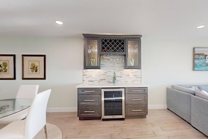 A modern kitchen with a built-in wine rack, a dishwasher, and a glass-top dining table with white chairs.