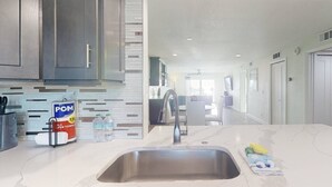 Cozinha moderna com pia de aço inoxidável, dosador de detergente POM e bancada de mármore.