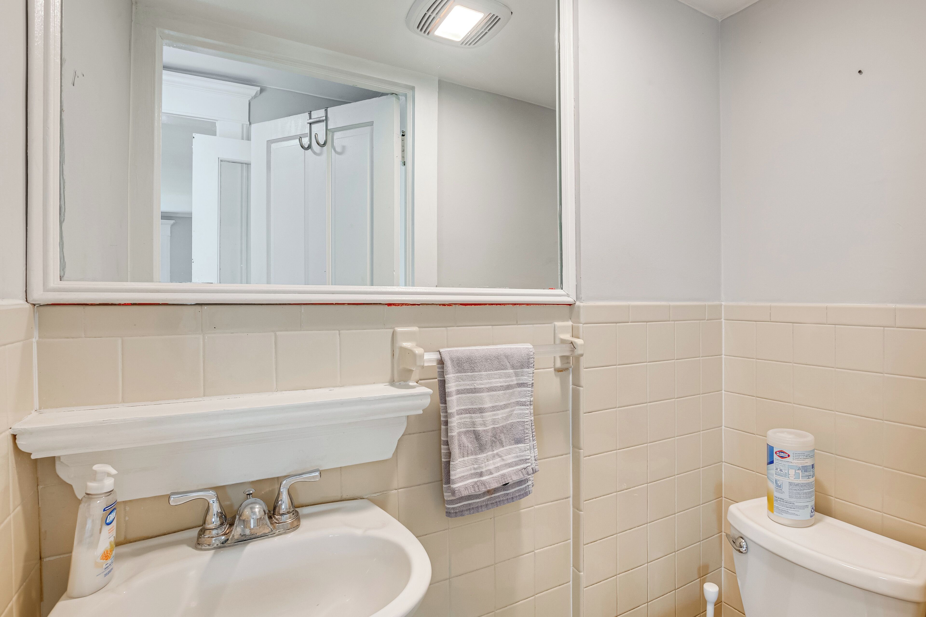 A bathroom with a white sink, mirror, and toilet.