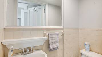 A bathroom with a white sink, mirror, and toilet.