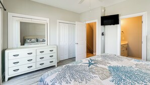 Een slaapkamer met een bed, een dressoir, een kledingkast en een aan de muur bevestigde televisie.