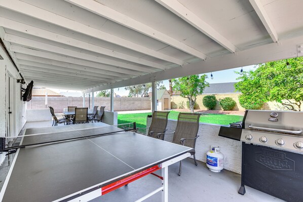 An outdoor patio with a ping pong table, chairs, a grill, and a propane tank. - Pool, Basketball + BBQ! Glendale Group Getaway (Glendale)