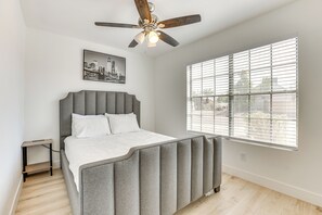 A bedroom with a bed, a ceiling fan, a window with blinds, a bedside table, and a wall-mounted picture. - Pool, Basketball + BBQ! Glendale Group Getaway (Glendale)