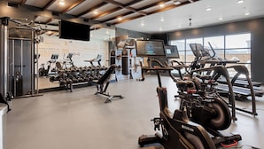 Un gimnasio con cintas de correr, bicicletas estáticas y máquinas de pesas.