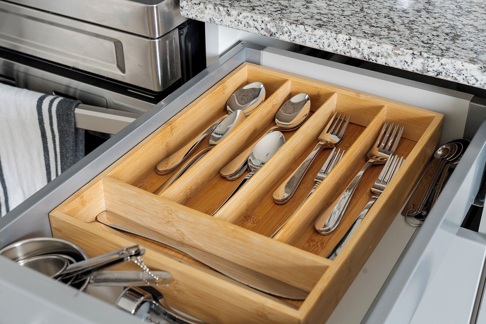 A drawer with neatly organized silverware, including spoons, forks, and knives.