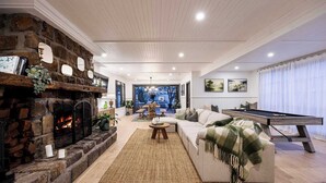 A spacious living room with a stone fireplace, a pool table, and a cozy seating area.