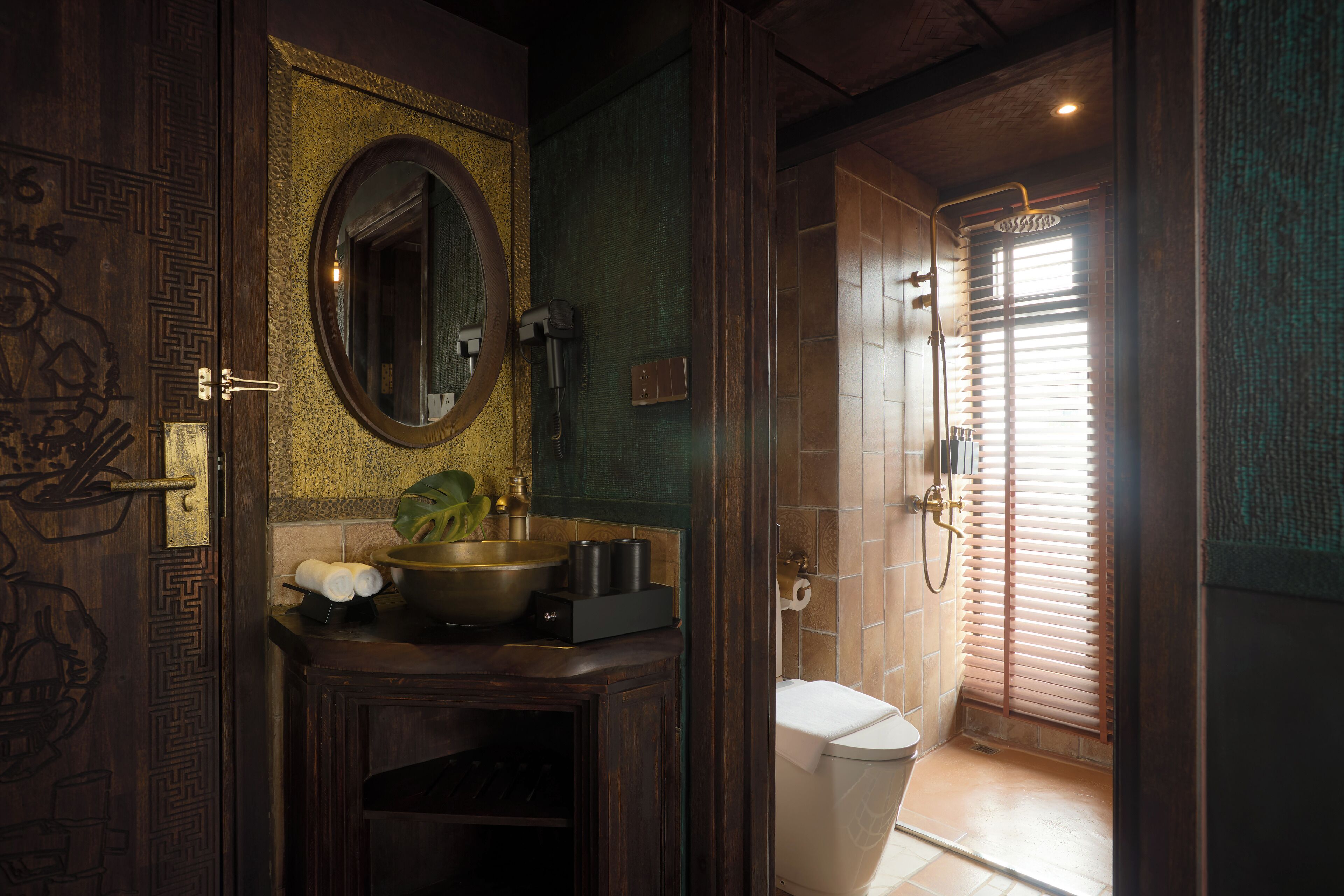 A bathroom with a wooden vanity, a sink, a mirror, and a shower area with a window.
