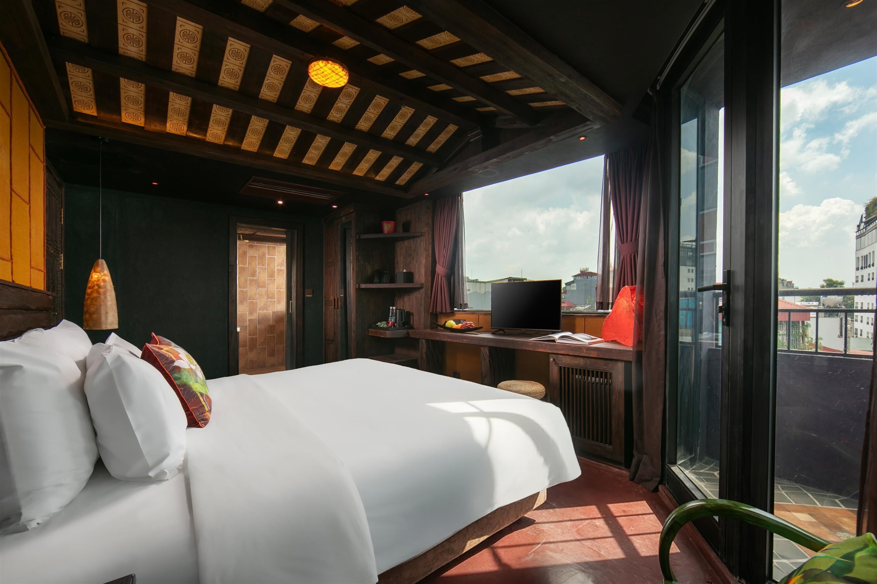 A bedroom with a bed, a desk, and a large window.