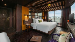 Habitación de hotel con una cama grande, un escritorio, una silla, un televisor y un balcón con vistas.